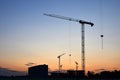 Jib construction tower cranes at a construction site on the sunset and blue sky background Royalty Free Stock Photo