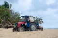 Tractor on resort beach clearing weed