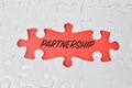 Jigsaw puzzle with the word PARTNERSHIP written on a red background. The business concept