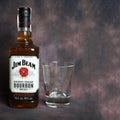 Jim Beam whiskey bottle and a glass for whiskey on dark vintage background