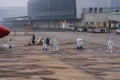 Customs officer and immigration officers in full protection safety suits and face shields leaving an airplane