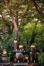 Jizo Bosatsu stone monk statues with bib and hat under tree in g