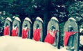 Jizo or stone statue wearing red apron under snow in vintage sty