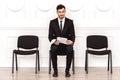 Job interview. Man sitting isolated on white waiting with resume looking camera pensive Royalty Free Stock Photo