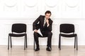 Job interview. Man sitting isolated on white waiting with resume touching chin smiling playful Royalty Free Stock Photo