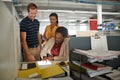 On the job late into the day. a three work colleagues talking together over a digital tablet.