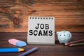 Job Scams. Cardboard notepad on wooden texture table