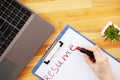 Job search. Female hand writes resume with lipstick on white sheet of paper. Wooden office desk with laptop, smartphone