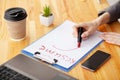 Job search. Female hand writes resume with lipstick on white sheet of paper. Wooden office desk with laptop, smartphone