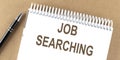 JOB SEARCHING text on a notepad with pen, business