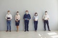 Job seekers in face masks waiting for job interview standing in corridor keeping safe distance Royalty Free Stock Photo