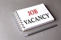 JOB VACANCY word on notebook on grey background