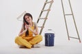 Job well done. Beautiful brunette in yellow uniform and blue colored bucket sits near the ladder Royalty Free Stock Photo