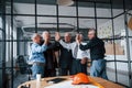 Job well done, gives high five to each other. Aged team of elderly businessman architects stands in the office together