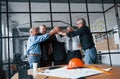 Job well done, gives high five to each other. Aged team of elderly businessman architects stands in the office together