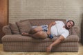 A jobless and lazy couch potato naps on the sofa still holding his phone Royalty Free Stock Photo