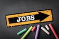 Jobs. Yellow directional arrow with text on a dark chalkboard background Royalty Free Stock Photo