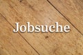 `Jobsuche` white text on a wooden background. Translation: Job search