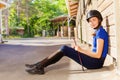 Jockey girl sitting outside a box stall with whip Royalty Free Stock Photo