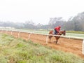 A Jockey riding a racing horse early  morning on race course track Royalty Free Stock Photo