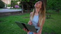 Girl chatting with laptop leaning on tree in park.