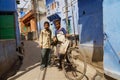 Teenagers with an old bicycle stand at the narrow street with blue painted houses in Jodhpur, India. Royalty Free Stock Photo