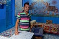 Man in a Jodhpur blue house with elephants on the wall