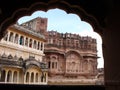 Impressive reddish-toned facade seen from an archway of the Mehrangarh Fort in the blue city of Jodhpur, India