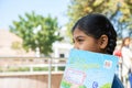 Jodhpur, Rajasthan, India - Jan 10th 2020: Closeup of indian happy student school girl holding exercise notebook cover her face,