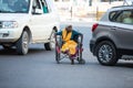 Jodhpur, Rajasthan, India - May 20 2020: Poor helpless handicapped old woman sitting in wheelchair wearing mask roaming on road