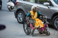 Jodhpur, Rajasthan, India - May 20 2020: Poor helpless handicapped old woman sitting in wheelchair wearing mask roaming on road