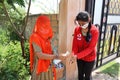 Jodhpur, Rajasthan, India, September 13,2020: Traditional woman in veil sanitizing hand of young girl before entering in school, s