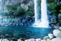 Joengbang waterfall into a deep blue pool in Seogwipo, Jeju Island, South Korea Royalty Free Stock Photo