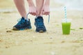 Jogger with green vegetable smoothie, tying sport running shoes laces Royalty Free Stock Photo