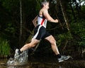 Jogger in a jump through a streambed