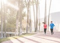 Joggers couple running outdoor in city track together - Sporty happy people training at morning in tropical place - Healthy