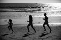 Joggers family have fun on beach run and jump at sunset. Father, mother, baby son run. Child jump with fun by water pool Royalty Free Stock Photo