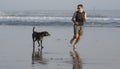 Jogging Summer workout with dog - young attractive and fit runner man training on beautiful beach running barefoot free and happy Royalty Free Stock Photo