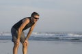 Jogging Summer workout - young attractive and fit runner man training on beautiful beach breathing tired and exhausted cooling off Royalty Free Stock Photo