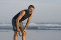 Jogging Summer workout - young attractive and fit runner man training on beautiful beach breathing tired and exhausted cooling off Royalty Free Stock Photo