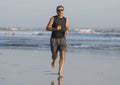 Jogging Summer workout - young attractive and fit runner man training on beautiful beach running barefoot free and happy by the Royalty Free Stock Photo