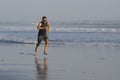 Jogging Summer workout - young attractive and fit runner man training on beautiful beach running barefoot free and happy by the Royalty Free Stock Photo