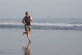 Jogging Summer workout - young attractive and fit runner man training on beautiful beach running barefoot free and happy by the Royalty Free Stock Photo