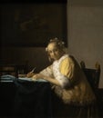 Lady writing a letter in yellow by Dutch golden age painter Johannes Vermeer