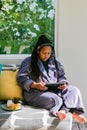 Young African woman in bath robe watching streaming service on tablet computer at spa resort