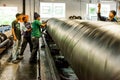 Diverse workers inside a rubber and pipe fabrication assembly line in a factory