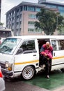 Mini bus taxi with passenger climbing out.