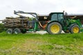 John Deer tractor on a farm with trailer loaded with tree trunks attached Royalty Free Stock Photo