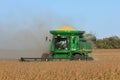 John Deere Combine cutting Soybeans in a farm field in the fall with blue sky.