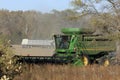 John Deere Combine cutting Soybeans in a farm field in the fall with blue sky.